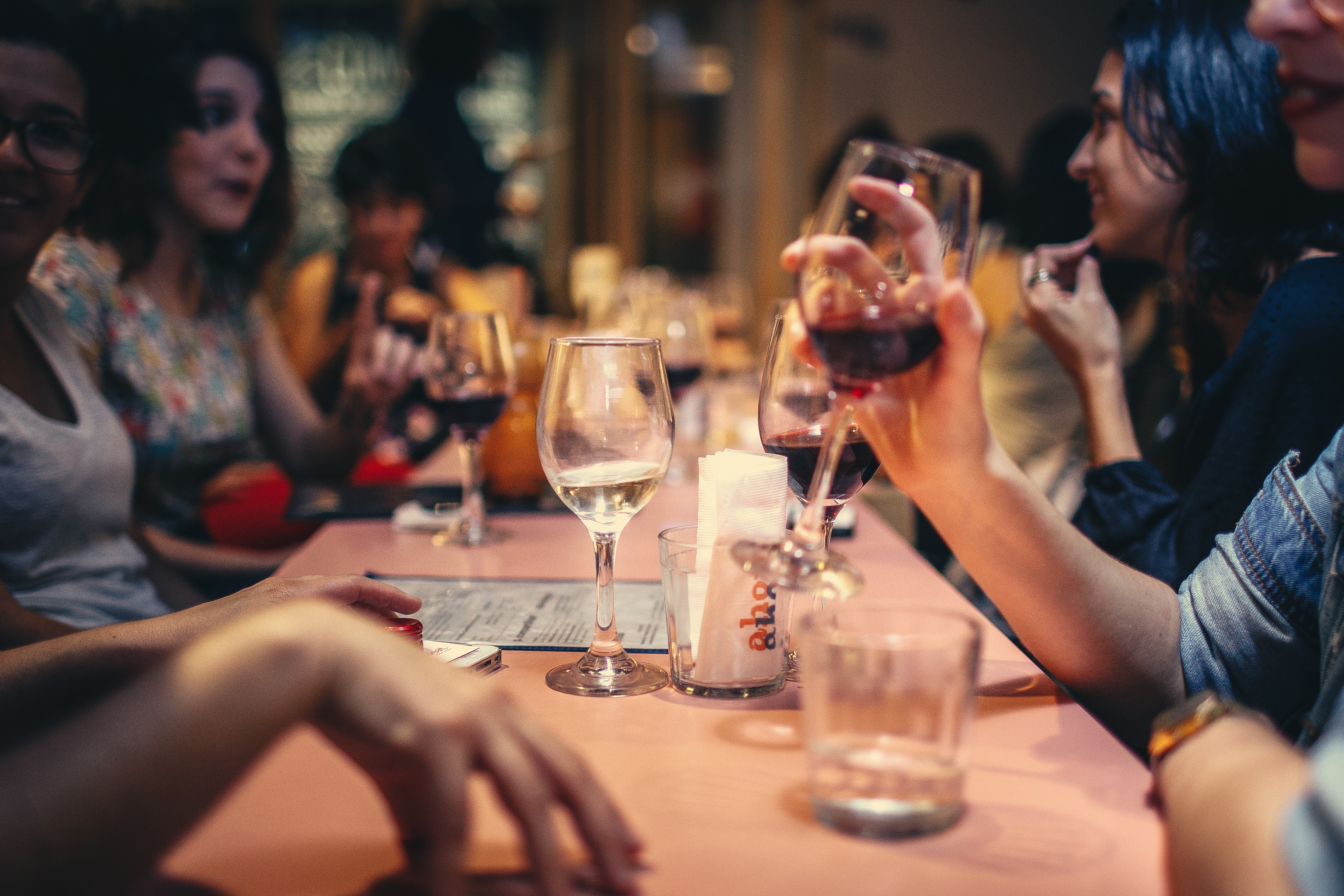 friends talking and drinking wine around a large restaurant table