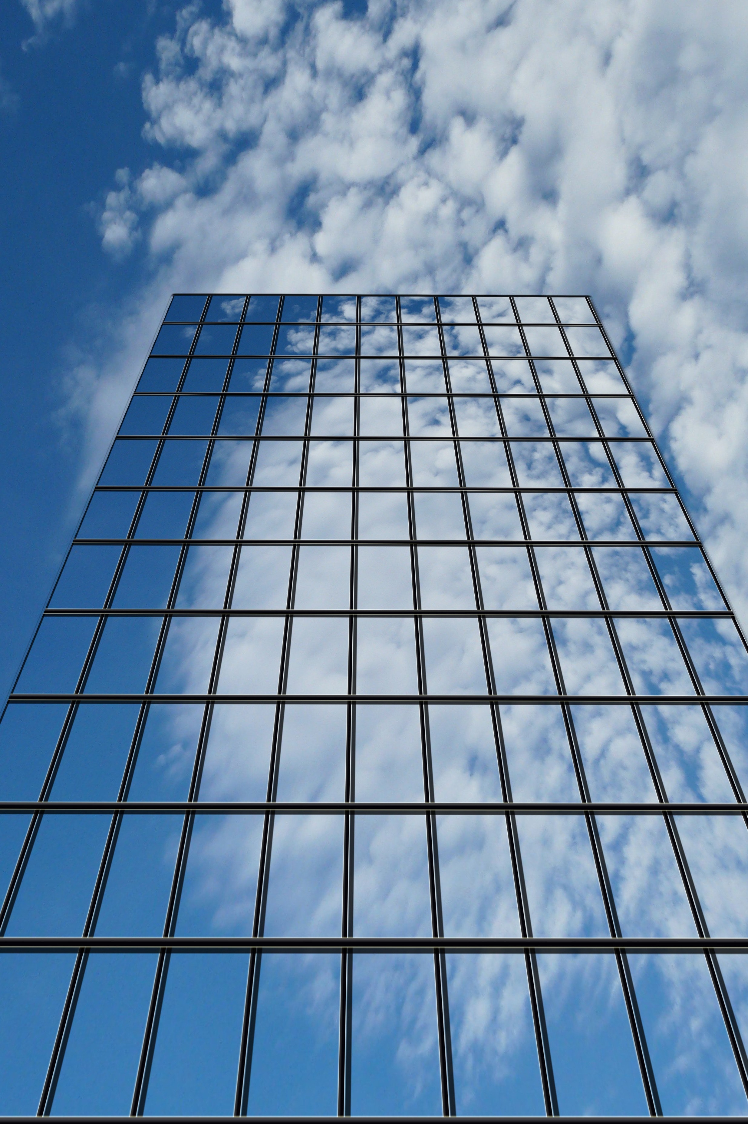 a building with all glass windows reflecting clouds and blue sky